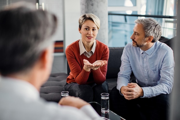 Midden volwassen koppel in gesprek met financieel adviseur tijdens een vergadering op kantoor