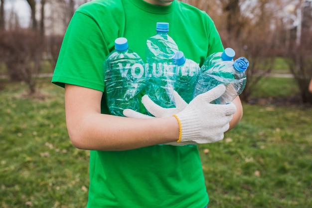 Milieu en vrijwilligersconcept met de mens die flessen verzamelt