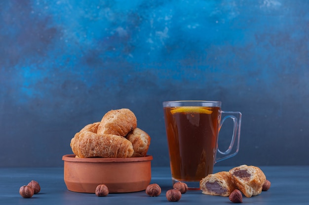 Mini croissants van bladerdeeg met een gouden korst en een kopje thee.