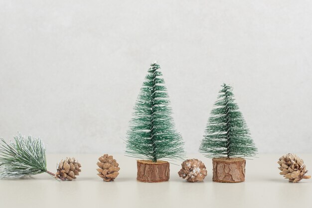 Mini kerstbomen en dennenappels op beige ondergrond