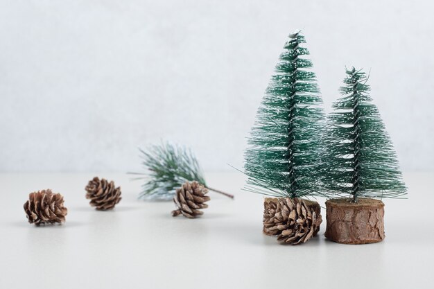 Mini kerstbomen en dennenappels op beige ondergrond