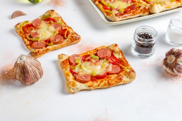 Gratis foto mini-pizza's van bladerdeeg met worstjes.