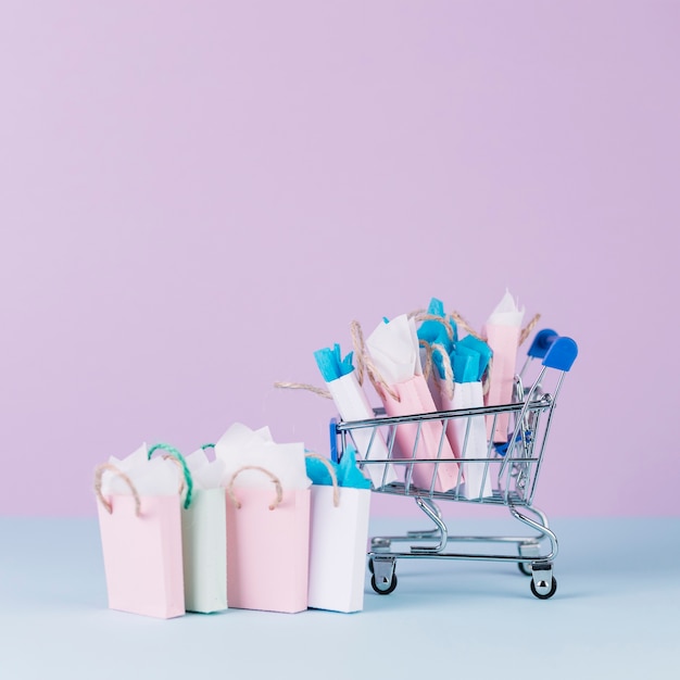 Gratis foto miniatuurkar die met document het winkelen zakken voor roze achtergrond wordt gevuld