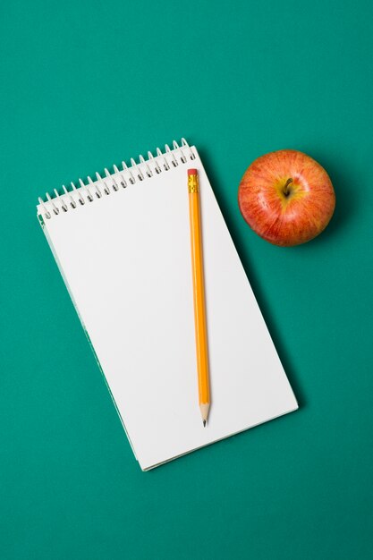 Gratis foto minimalistische bovenaanzicht apple en bureau benodigdheden