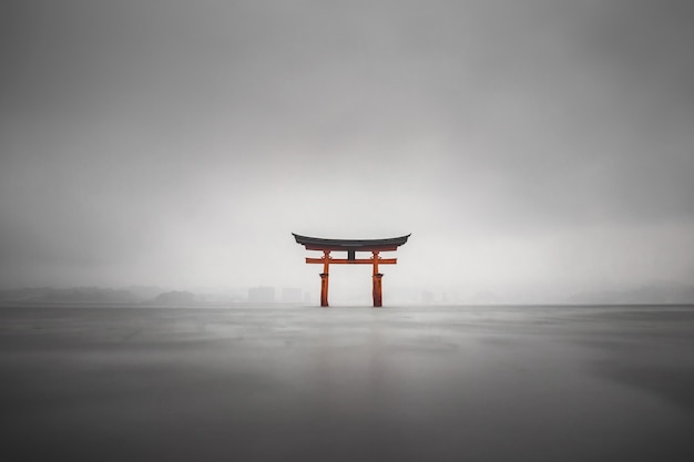 Mistig schot van de drijvende torii van Miyajima, Japan tijdens regen