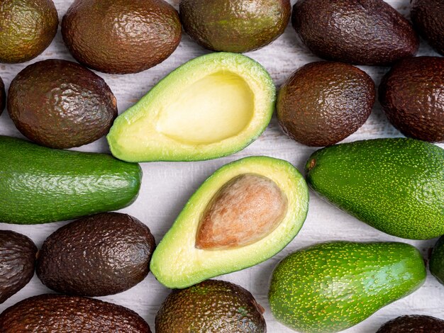 Mix van gescheurde en groene avocado's op een wit houten bord.