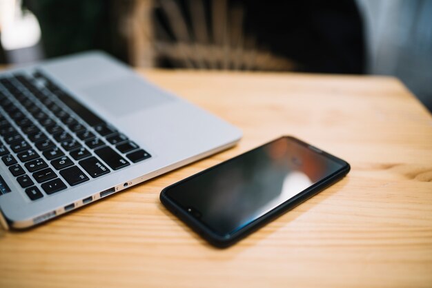 Mobiele telefoon en laptop aan tafel in straat café