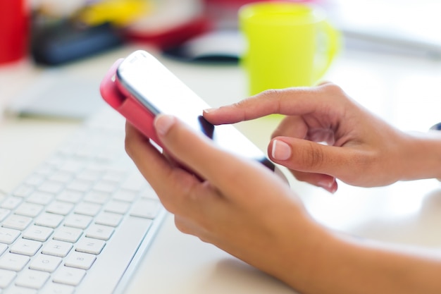 Mobiele telefoon in de hand van een vrouw. Binnenbeeld.