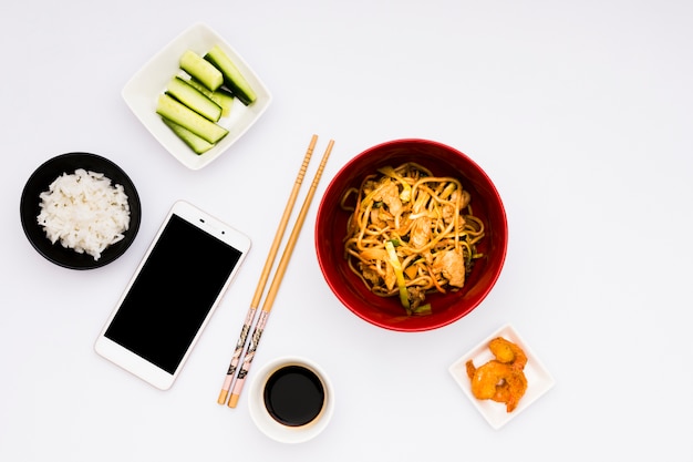 Mobiele telefoon met lekker Aziatisch eten over wit oppervlak