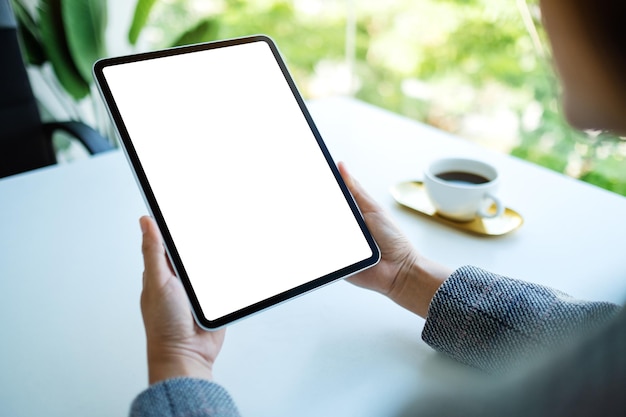 Mockup-afbeelding van een vrouw met een digitale tablet met een leeg wit bureaubladscherm op kantoor Premium Foto