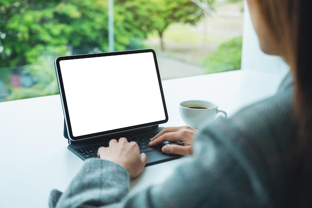 Mockup-afbeelding van een zakenvrouw die een digitaal tablettoetsenbord gebruikt en typt met een leeg wit bureaubladscherm als een computer-pc op kantoor