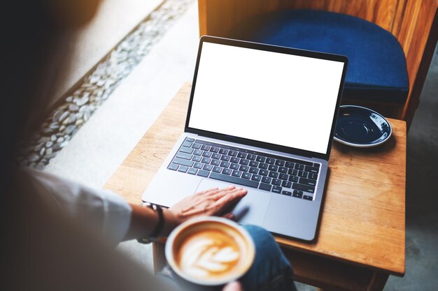 Mockup-afbeelding van een zakenvrouw die laptop-touchpad gebruikt en aanraakt met een leeg wit desktopscherm in café Premium Foto