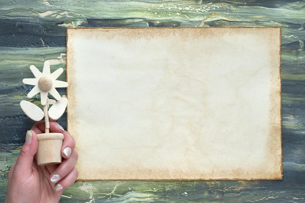 Mockup copyspace op oude patchment beige papieren pagina hand houden natuurlijke houten bloem figuur