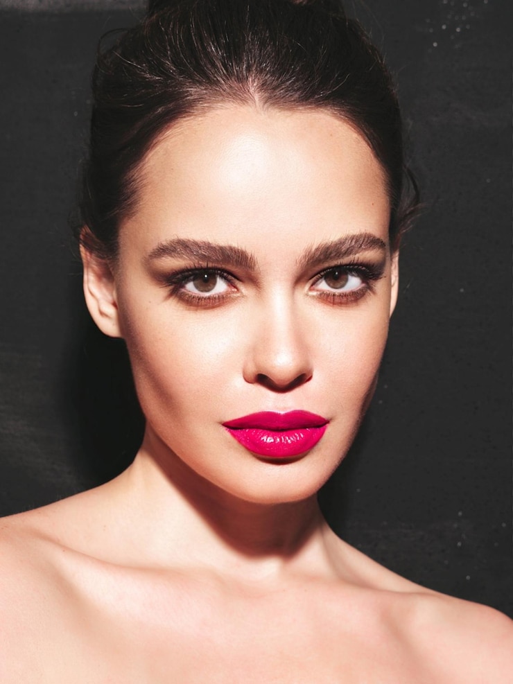 Gratis Foto mode schoonheid portret van jonge brunette vrouw met stijlvolle avond make-up en perfecte schone huid sexy model met haar in een broodje poseren in studio in de buurt van zwarte muur met roze heldere natuurlijke lippen