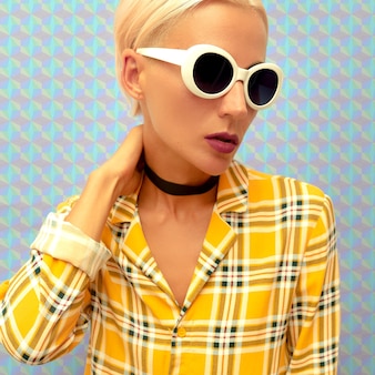 Modeblonde in stijlvolle zomeraccessoires. choker en zonnebril. trend geruit overhemd Premium Foto