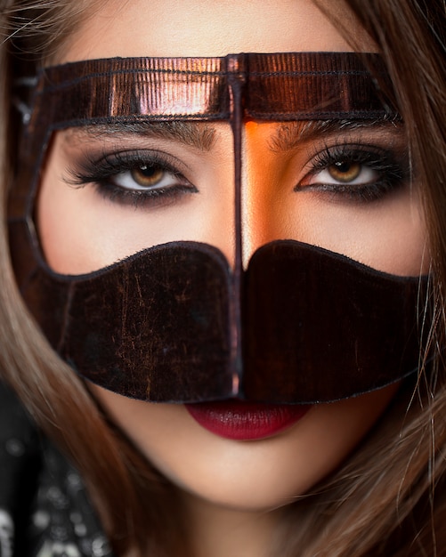 Model in een gouden masker accentueren haar ogen make-up
