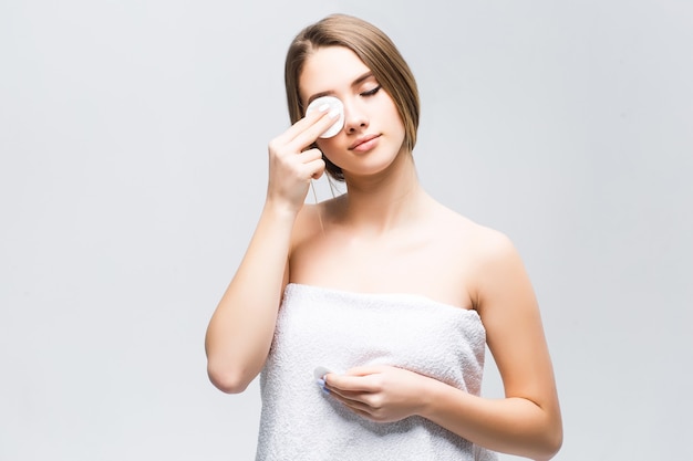 Model met natuurlijke make-up maakt haar gezicht schoon met een witte spons op het oog