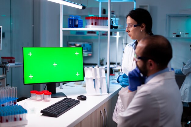 Modern medisch onderzoekslaboratorium met twee wetenschappers die een computer gebruiken met een groen Chromakey-scherm