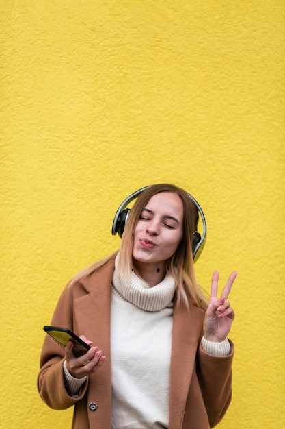Gratis foto moderne blondevrouw die aan muziek op hoofdtelefoons luisteren