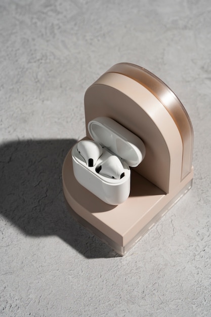 Moderne draadloze oortelefoons met hoesje weergegeven op een rond podium met zachte schaduwen