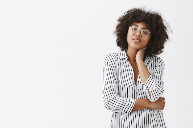 moderne, goed uitziende en stijlvolle vrouwelijke manager in gestreepte blouse die de nek aanraakt en het hoofd kantelt waardoor massage moe wordt van het zitten en werken de hele dag