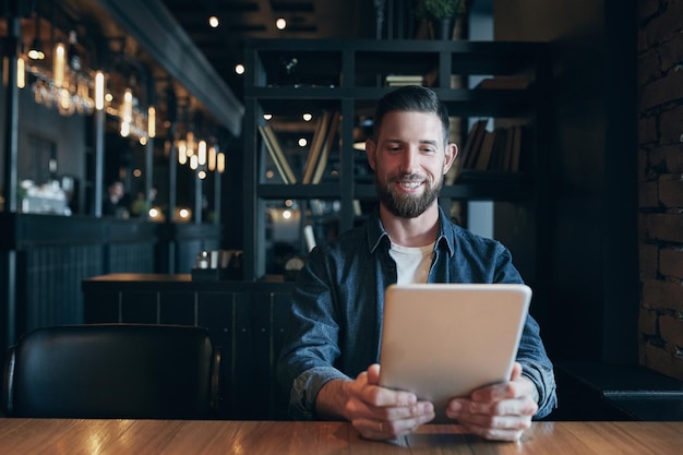 Moderne hipster zakenman die koffie drinkt in het stadscafé tijdens de lunch en aan het werken is op een tablet. Freelancer