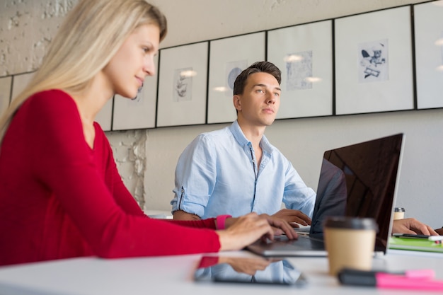 Moderne jonge man en vrouw die op laptop in open ruimte co-working kantoorruimte werkt