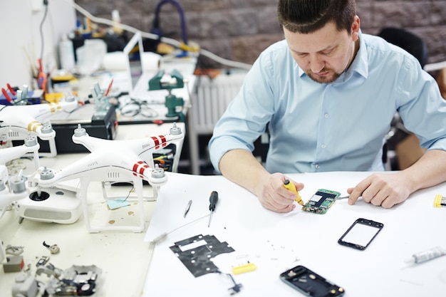 Gratis foto moderne man aan het werk in elektronica servicewinkel