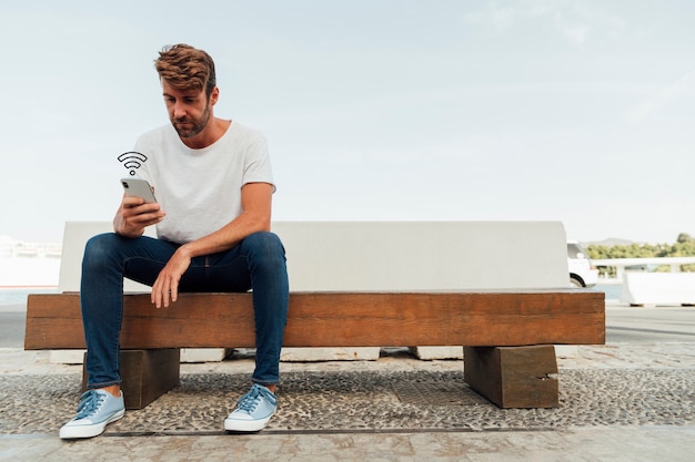 Moderne man doorbladeren telefoon op een bankje