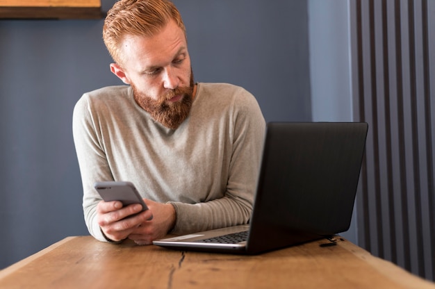 Gratis foto moderne mens die zijn laptop bekijkt