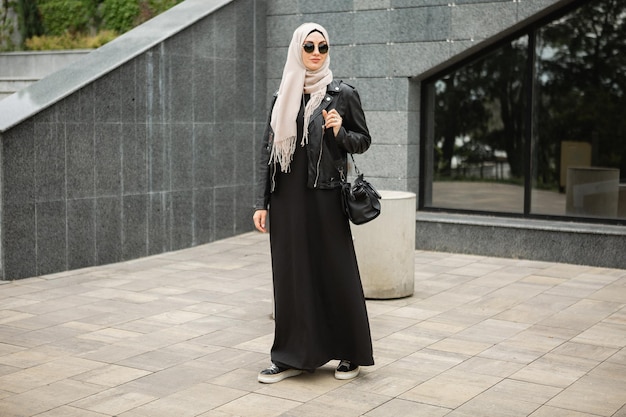 Gratis foto moderne stijlvolle moslimvrouw in hijab in stadsstraat