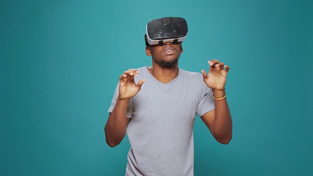 Moderne volwassene die plezier heeft met vr-brilspel op camera, speelt met visuele 3D-simulatie. Duizendjarige man met virtual reality-bril met interactieve visie en futuristische augmented software.
