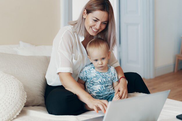 Moderne vrouw die met kind werkt. Multi-tasking, freelance en moederschap concept