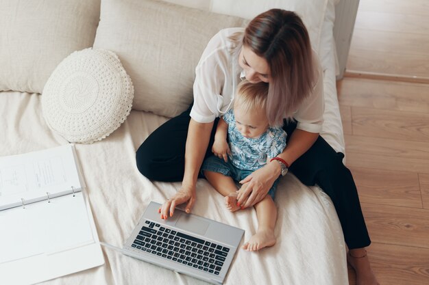 Moderne vrouw die met kind werkt. Multi-tasking, freelance en moederschap concept