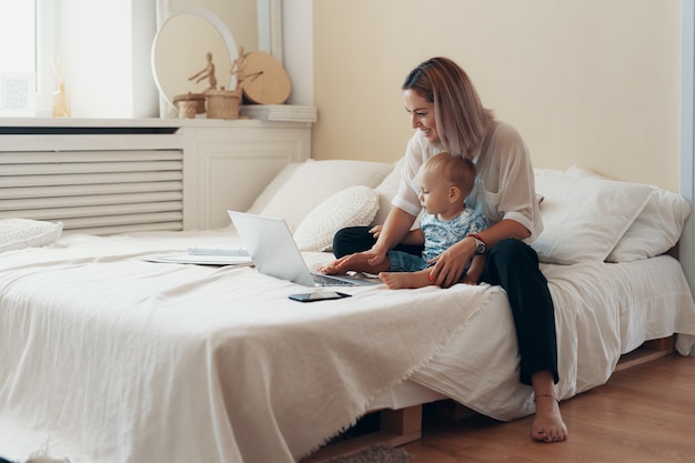 Moderne vrouw die met kind werkt. Multi-tasking, freelance en moederschap concept