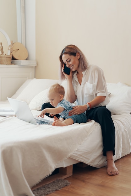 Moderne vrouw die met kind werkt. Multi-tasking, freelance en moederschap concept