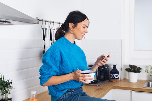 Gratis foto moderne vrouw die ontbijt in de keuken heeft