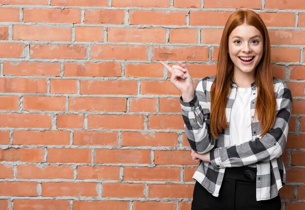 Moderne vrouw die op bakstenen muur richt