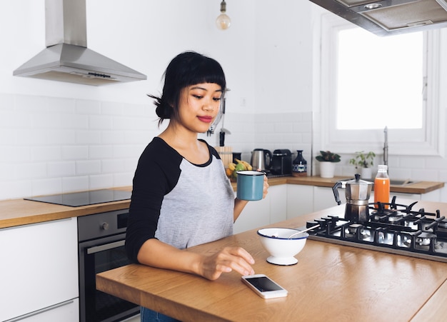 Moderne vrouw in de keuken met behulp van de mobiele telefoon