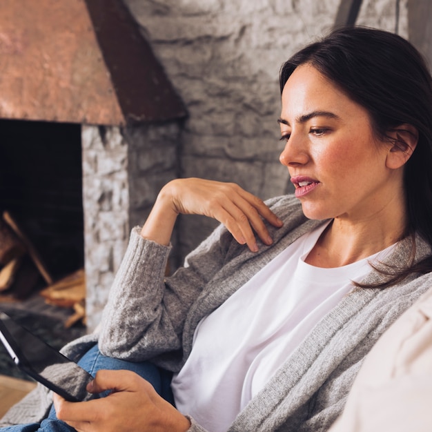 Gratis foto moderne vrouwenzitting op de bank die een tablet gebruiken