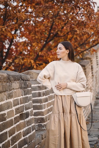 Modieus meisje die de grote muur van china bezoeken dichtbij peking tijdens de herfst