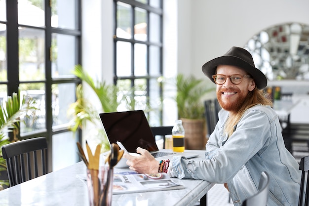 Modieuze hipster-man gekleed in een stijlvolle zwarte hoed en denimoverhemd