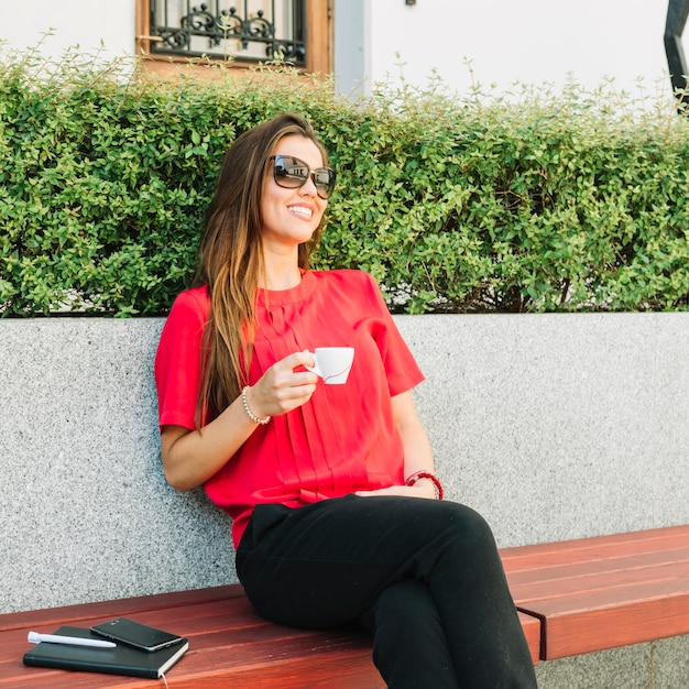 Gratis foto modieuze vrouwenzitting op bank het drinken koffie