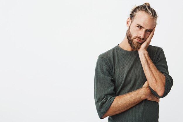 Moe aantrekkelijke man met stijlvolle kapsel en baard in grijs shirt uitgeput op zoek