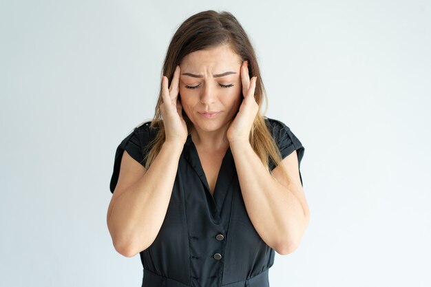 Moe benadrukt jonge vrouw in zwarte jurk gevoel hoofdpijn en het masseren van tempels.