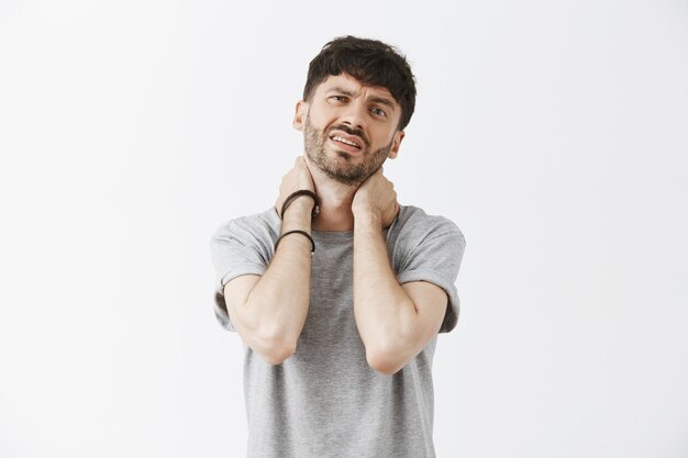 Moe en zieke knappe jongen poseren tegen de witte muur