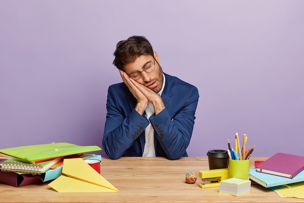 Moe overwerkte zakenman zit aan het bureau