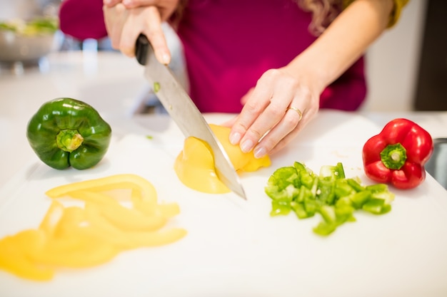 Moeder assisteren dochter in het snijden van groenten in de keuken