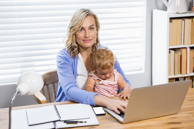 Moeder bedrijf baby meisje tijdens het gebruik van laptop