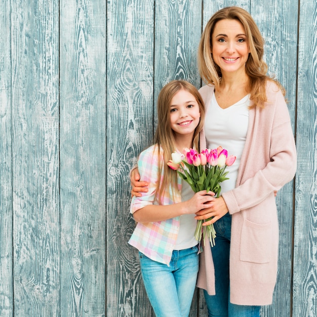 Moeder die dochter omhelst en tulpen houdt